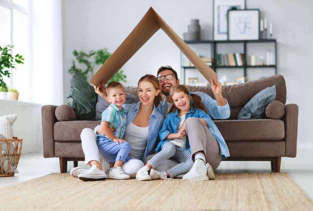 concept of housing and relocation. happy family mother father and kids with roof at a home